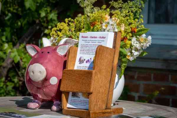 Spendenschwein, Flyer, Blumenstrauß auf Holztisch.